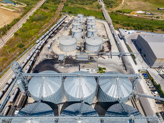 Industrial grain storage facility with silos and railway tracks in a rural area during daytime © DSMT