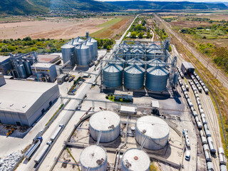 Industrial complex with storage silos and transport railway near a rural area © DSMT