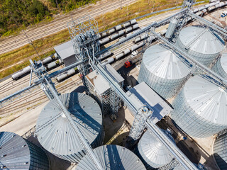 Large grain storage facility with silos and rail cars in a rural area during daylight © DSMT