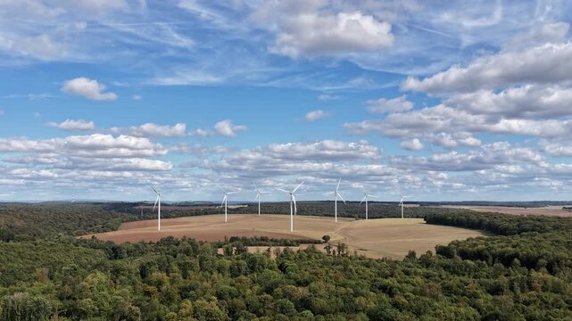 vue a&eacute;rienne du parc &eacute;olien d'Ottange en Moselle. effet hyper lapse sur les nuages qui avancent  et les pales d'&eacute;oliennes qui tournent tr&egrave;s vite. Ciel bleu nuageux en septembre 2026 France