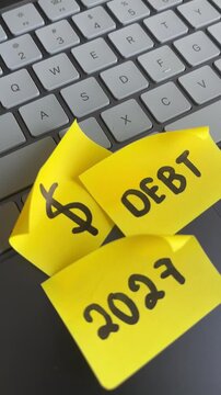 Debt dollar sign and 2027 sticky notes on laptop keyboard