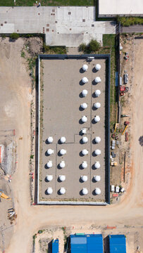 Aerial view of white antenna radomes arranged in a grid within a fenced industrial site near a data center construction project in Milan, Lombardy, Italy.