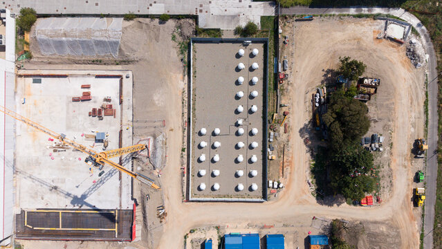 Aerial view of white antenna radomes arranged in a grid within an active industrial site near a data center construction project in Milan, Lombardy, Italy.