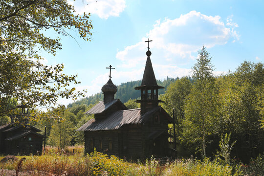 Wooden church on the background of a green forest on a clear sunny day, Perm region. Sights of Russia, World tourism.