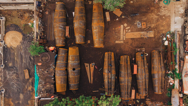 Aerial view of oil tanker components being fabricated and modified in an industrial yard with metal structures and workers in India.
