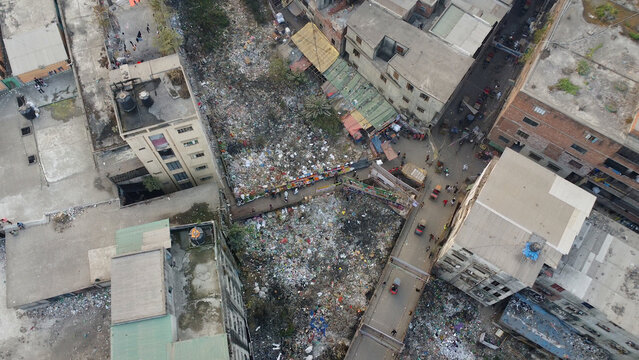 Aerial view of dense urban buildings, narrow streets with traffic, and significant waste accumulation in Dhaka, Dhaka Division, Bangladesh.
