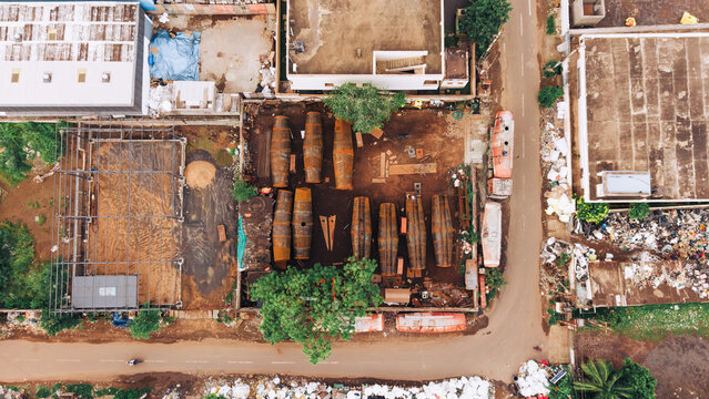 Aerial view of an industrial site where cylindrical oil tanker components are being modified and assembled, featuring metal structures and scattered materials in India.