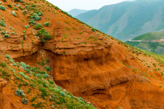 Eroded Hillside with Orange Soil and Sparse Vegetation in Kyrgyzstan