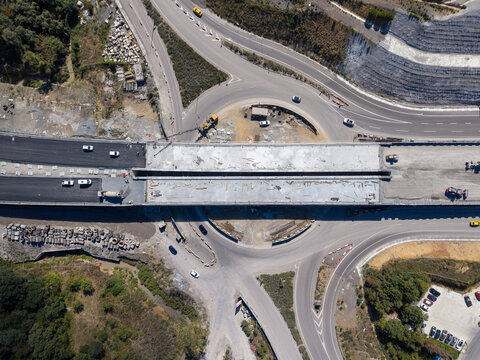 Aerial view of a highway bridge construction site with heavy machinery and vehicles navigating a roundabout in Istanbul, Istanbul, Turkiye.