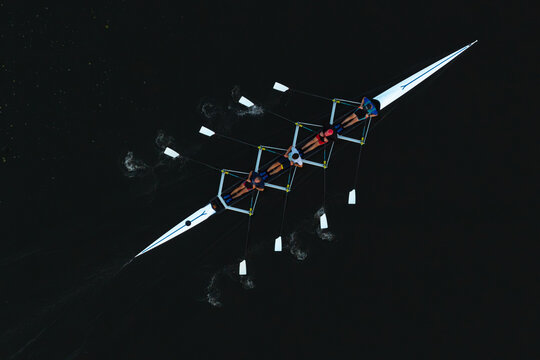 Aerial view of a rowing team in a scull boat gliding across dark water in Poland.