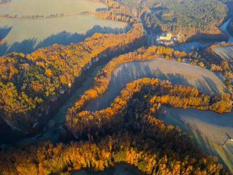 Aerial view of Kost Castle surrounded by dense autumn forests and a winding river in the countryside in Libosovice, Kralovehradecky kraj, Czechia.