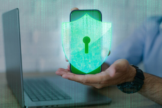 Businessman holding smartphone with glowing green shield and keyhole icon, representing mobile cybersecurity, data protection, digital privacy, and secure cloud network connectivity.