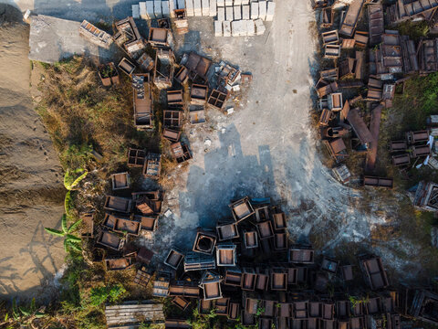 Aerial view of industrial molds and construction frames scattered across a dirt yard in Cilongok, Central Java, Indonesia.