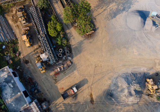 Aerial view of heavy construction machinery and piles of gravel at a quarry site in Cilongok, Central Java, Indonesia.