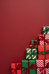 Naklejka premium Merry Christmas and Happy New Year stacked red and green gift boxes with ribbons and striped wrap on vertical red copyspace