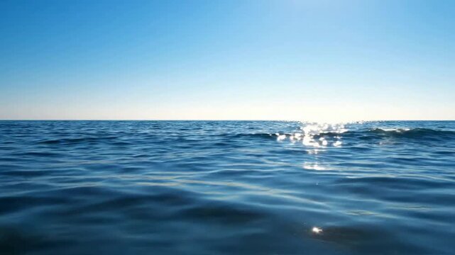 Serene ocean waves at sunset: sparkling blue sea surface background, with calm ripples, and golden sunlight reflections