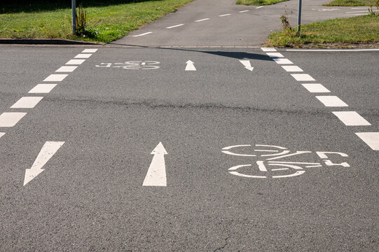 White painted bicycle icon and direction arrows marked on city asphalt street pavement. Clear urban road sign markings for cycling safety and transportation planning