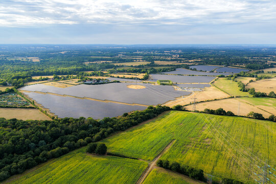 Aerial view of the Fresh Water Solar farm featuring rows of photovoltaic panels set within a rural landscape of green fields and woodland in Hook, England, United Kingdom.
