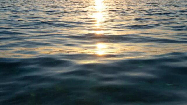 Golden sunset reflection on gentle ocean waves, serene sea surface background, sunrise