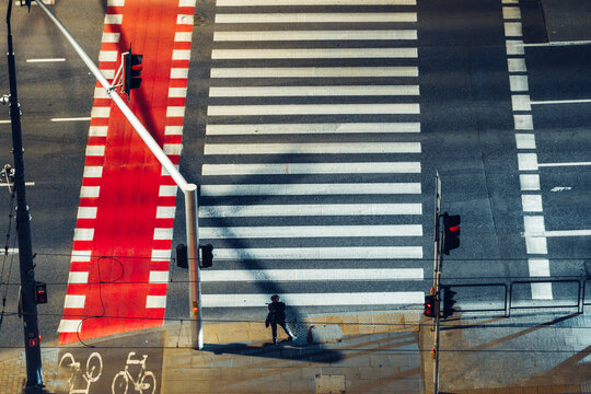 Aerial view of a pedestrian crosswalk with a red bicycle lane and traffic lights at night in Warsaw, Poland.