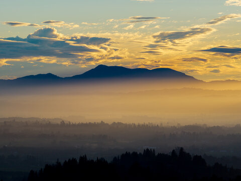 Aerial view of Sonoma County sunrise with golden light illuminating the mountain range and misty valley below in Sonoma County, California, United States.