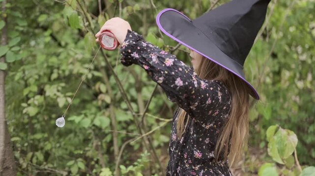 little sorceress performing magic ritual with crystal pendulum in magic forest, first romantic feelings, cute childhood fantasy story, pagan witchcraft ritual, learning through play imagination