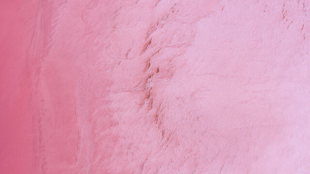 Aerial view of the vibrant pink salt crust and textured surface of Hutt Lagoon Pink Lake in Yallabatharra, Western Australia, Australia.