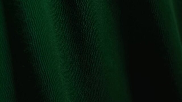 Dark green textured surface with bright light in abstract shadowy setting