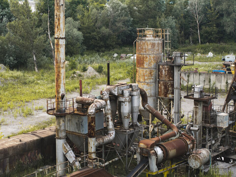 Aerial view of abandoned industrial processing plant with rusted pipes, tanks and mechanical equipment