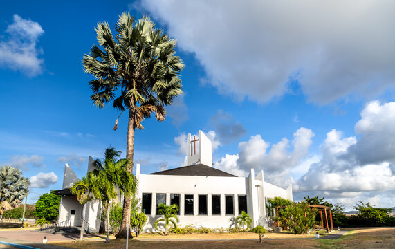 Exterior view of the modern Holy Family Catholic Cathedral surrounded by palm trees under a blue sky in Saint John's, Antigua and Barbuda.