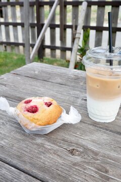 ラズベリーマフィンとアイスカフェオレ。屋外の木製テーブル