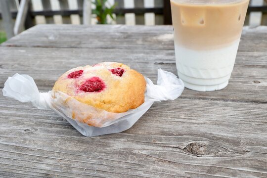 ラズベリーマフィンとアイスカフェオレ。屋外の木製テーブル