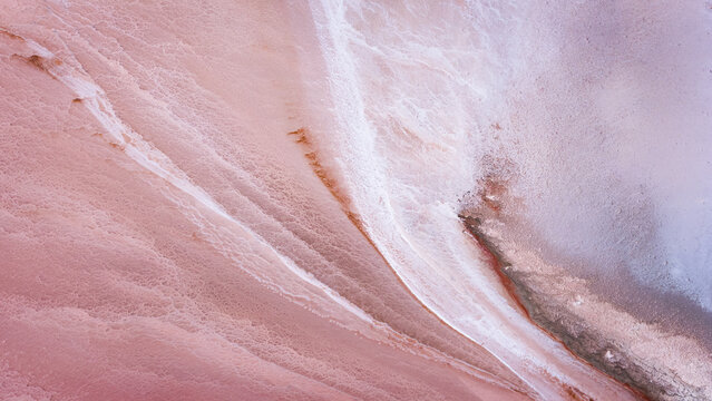 Aerial view of Hutt Lagoon Pink Lake showing vibrant pink salt crusts and white mineral deposits in an abstract landscape pattern in Yallabatharra, Western Australia, Australia.
