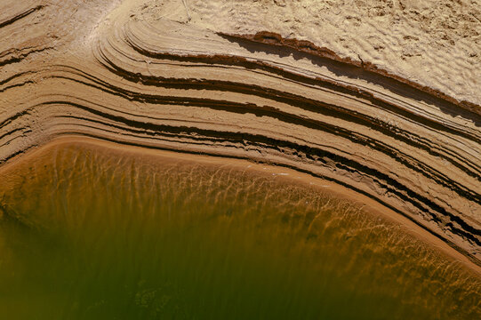 Aerial view of the layered sand formations and ripples in the water of the Adrar valley, Mauritania.