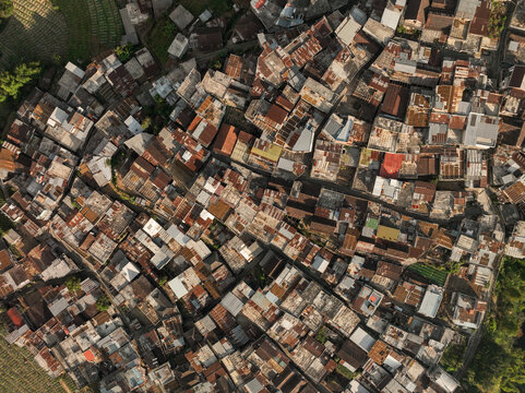 Aerial view of the dense residential rooftops of Kruwisan village, surrounded by agricultural fields in Kledung, Central Java, Indonesia.