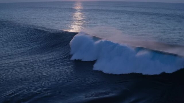 Ocean wave with sea spray under reflected sunlight across open blue water