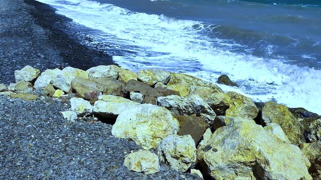 High Angle View of Sea Waves Crashing Against Big Rocks and Pebble Shoreline, White Foam Water Flowing on Coastal Breakwater