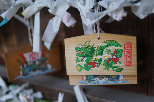 Traditional Japanese wooden ema plaque with a painted green dragon illustration hanging at a shrine