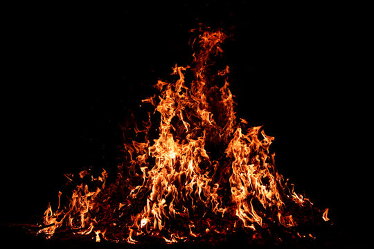 Burning embers beneath bright fire. Embers glowing beneath bonfire flames. Glowing embers with blazing fire. Embers burning beneath flames in motion.