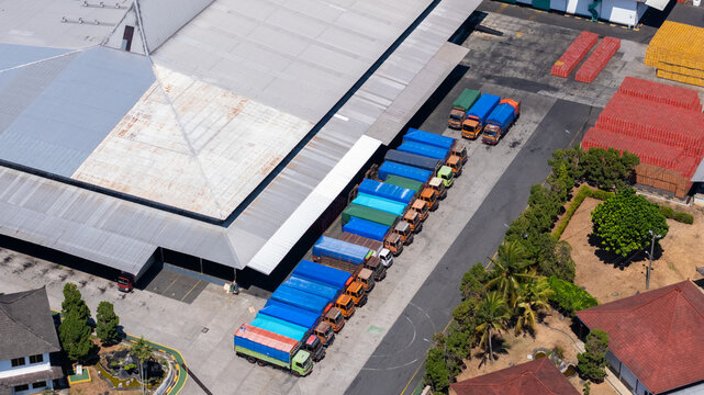 Aerial view of a line of colorful cargo trucks parked at a large industrial warehouse facility in Salatiga, Central Java, Indonesia.