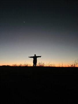 Person Standing with Arms Outstretched in a Dramatic Sunset Sky, Paraguay