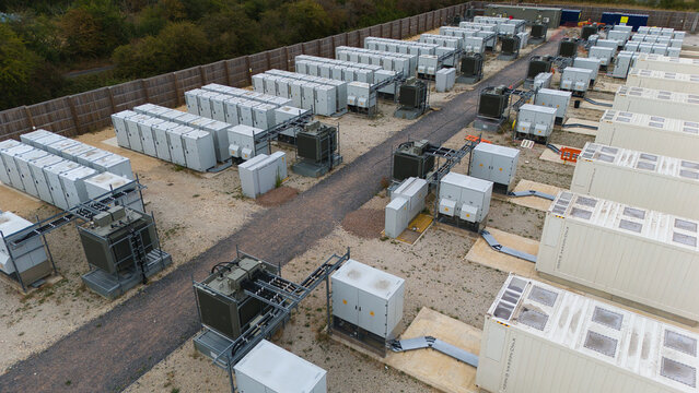 Aerial view of Battery Energy Storage facility and Substation with rows of white storage containers, electrical transformers, and gravel pathways in Stony Stratford, England, United Kingdom.