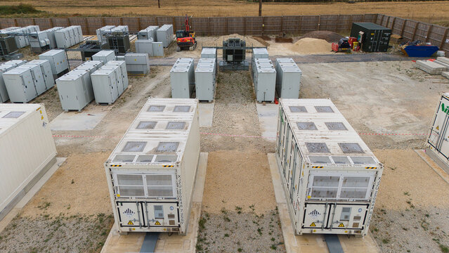 Aerial view of a Battery Energy Storage facility and Substation with rows of white energy storage containers and electrical equipment, Stony Stratford, England, United Kingdom.