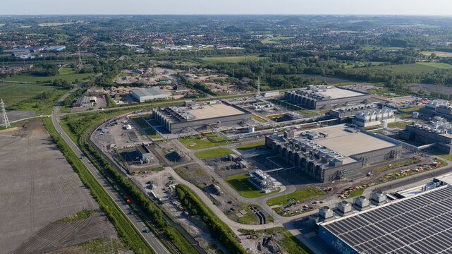 Aerial view of data center complex featuring large industrial buildings, cooling systems, and solar panels in Saint-Ghislain, Region wallonne, Belgium.