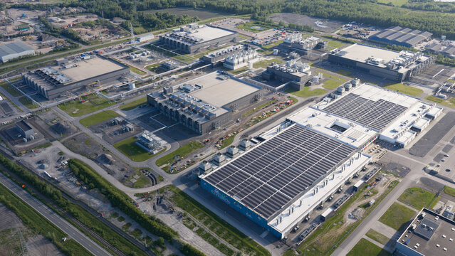 Aerial view of data center complex featuring large industrial buildings, cooling systems, and solar panels in Saint-Ghislain, Region wallonne, Belgium.