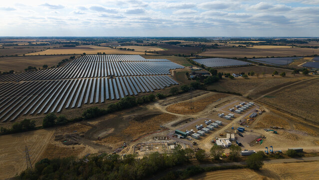 Aerial view of Eaton Socon Substation, solar farm and Battery Energy Storage Systems with rows of solar panels, electrical infrastructure, and fields in St. Neots, England, United Kingdom.