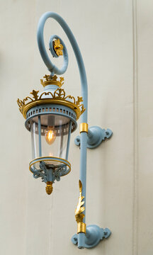 Neoclassical ancient European architecture. Wall lamp lantern on balcony architecture. Elegant wall lamp in classicism or baroque style. Gilded decorative details and metal balcony railing