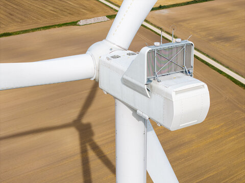 Aerial view of a wind turbine nacelle with blades and technical equipment above agricultural fields in Targale parish, Ventspils Municipality, Latvia.