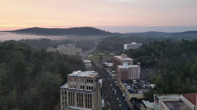 Aerial view of downtown city with foggy hills at dawn.
