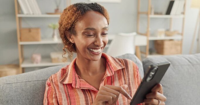 Smiling woman taps tablet on sofa indoors. She enjoys a happy moment in a cozy room, using touchscreen for digital communication and lifestyle content. Modern home happiness lifestyle concept.